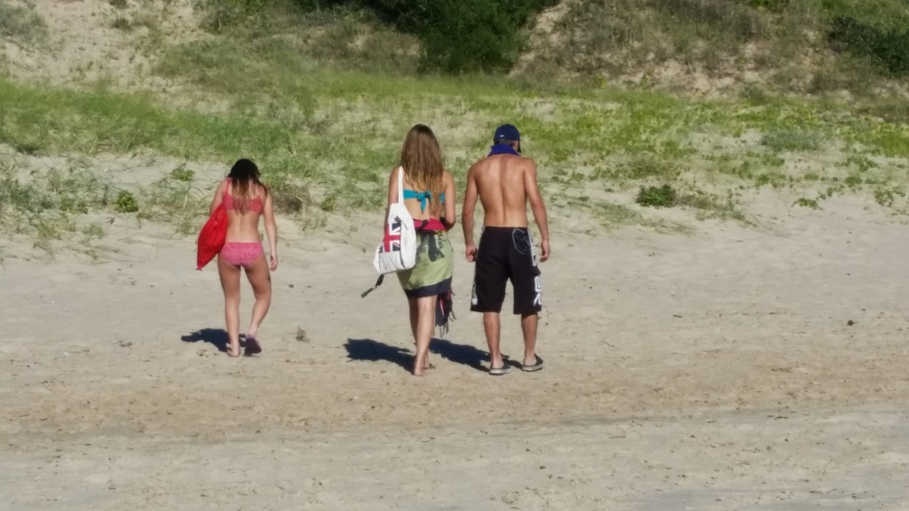 dos mujeres jovenes y un jove caminando de espaldas por la playa

two young women and a young boy walking on the beach